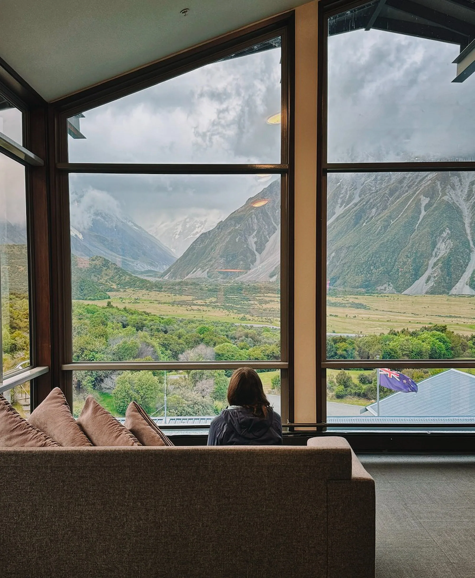 A guest looking toward the cloud-covered mountains through the Hermitage windows