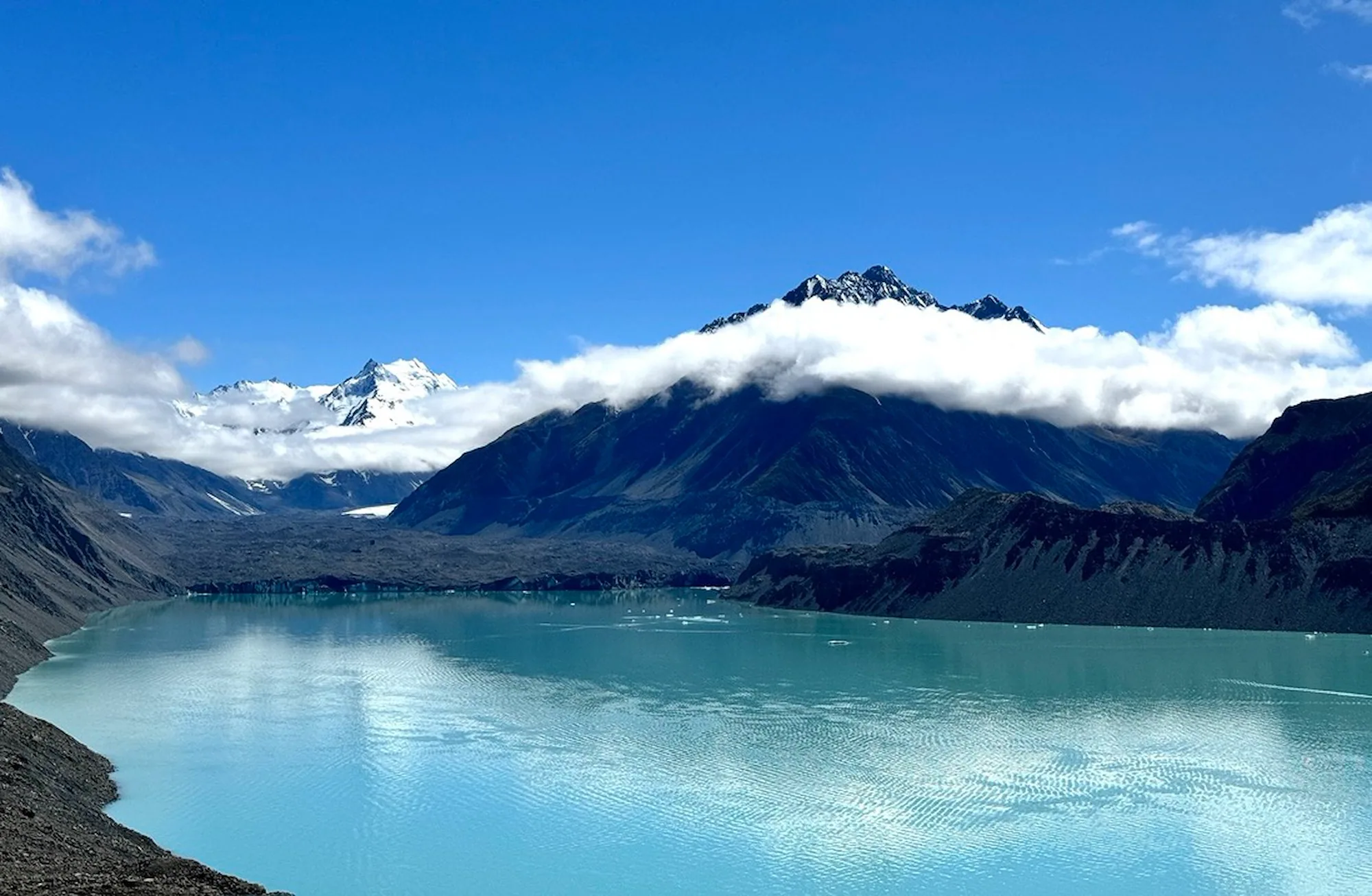 The turquoise Tasman Glacier Lake beneath a band of clouds
