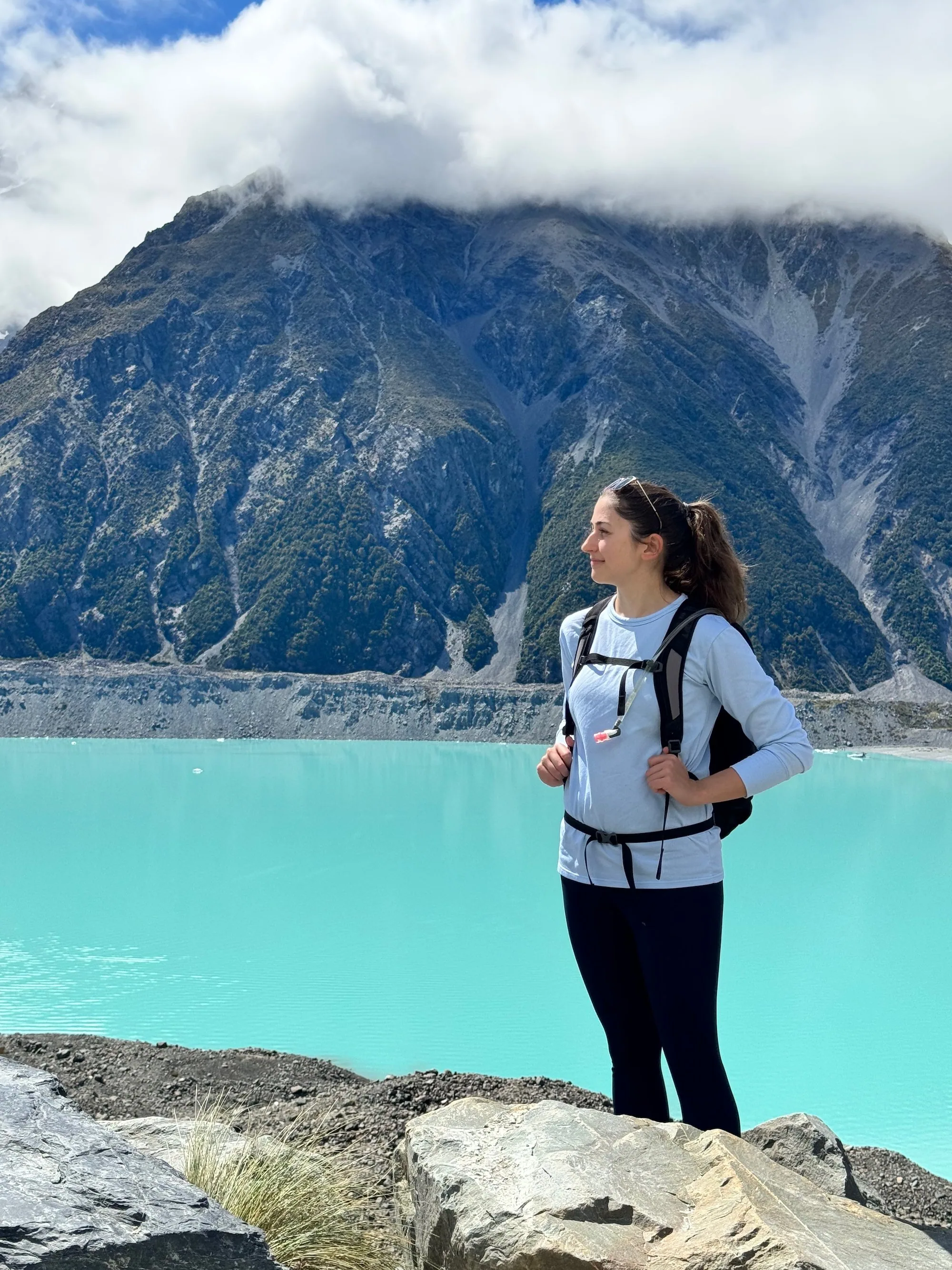 A hiker standing above the turquoise Tasman Glacier Lake