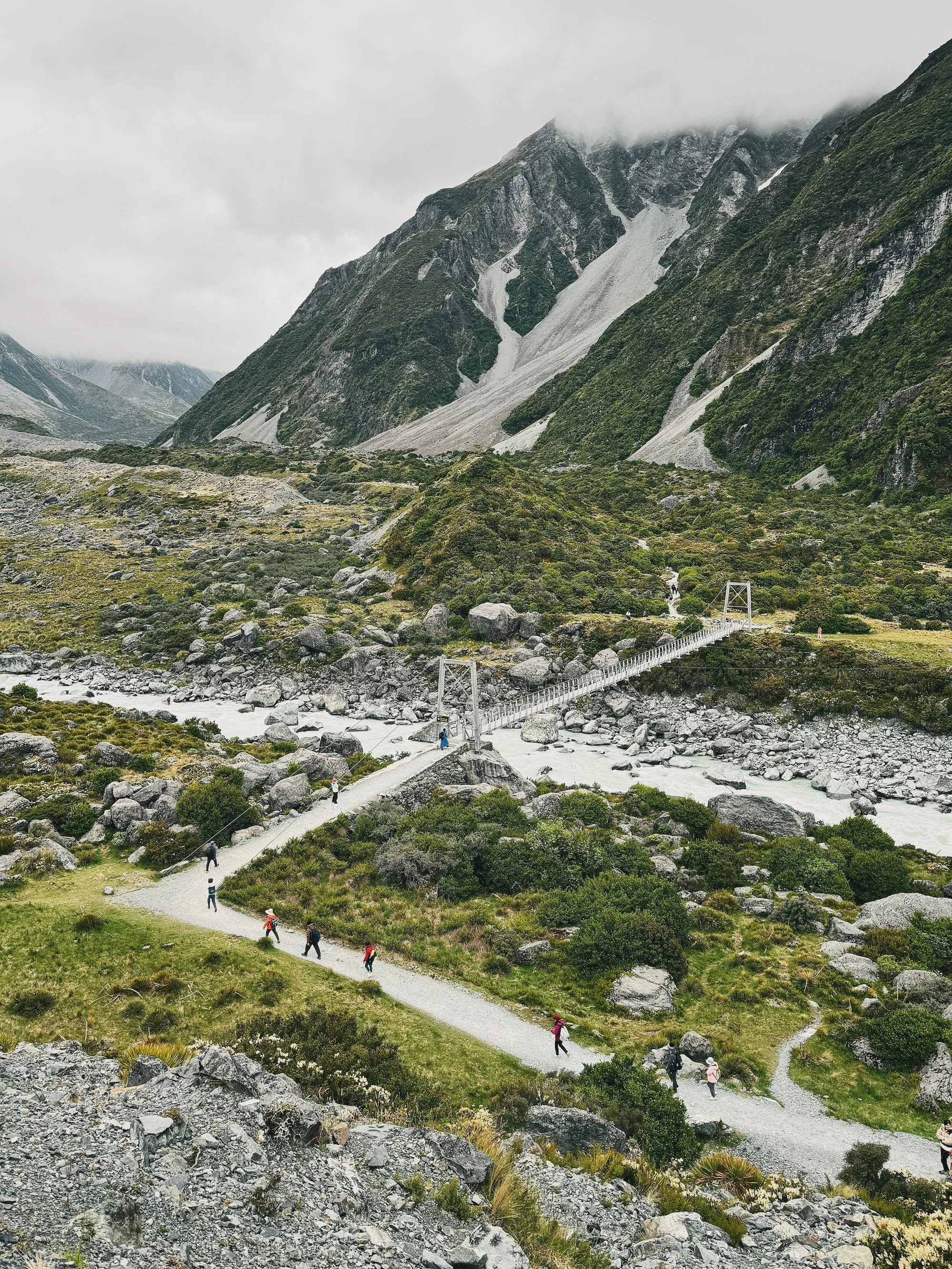 A hiker crossing the First Swing Bridge above the Hooker River