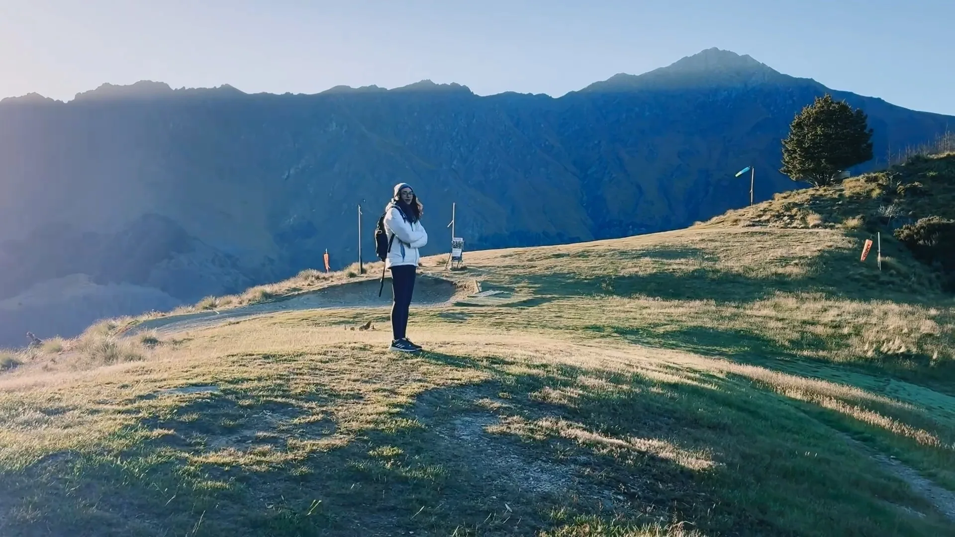 A hiker standing at the grassy paragliding launch site