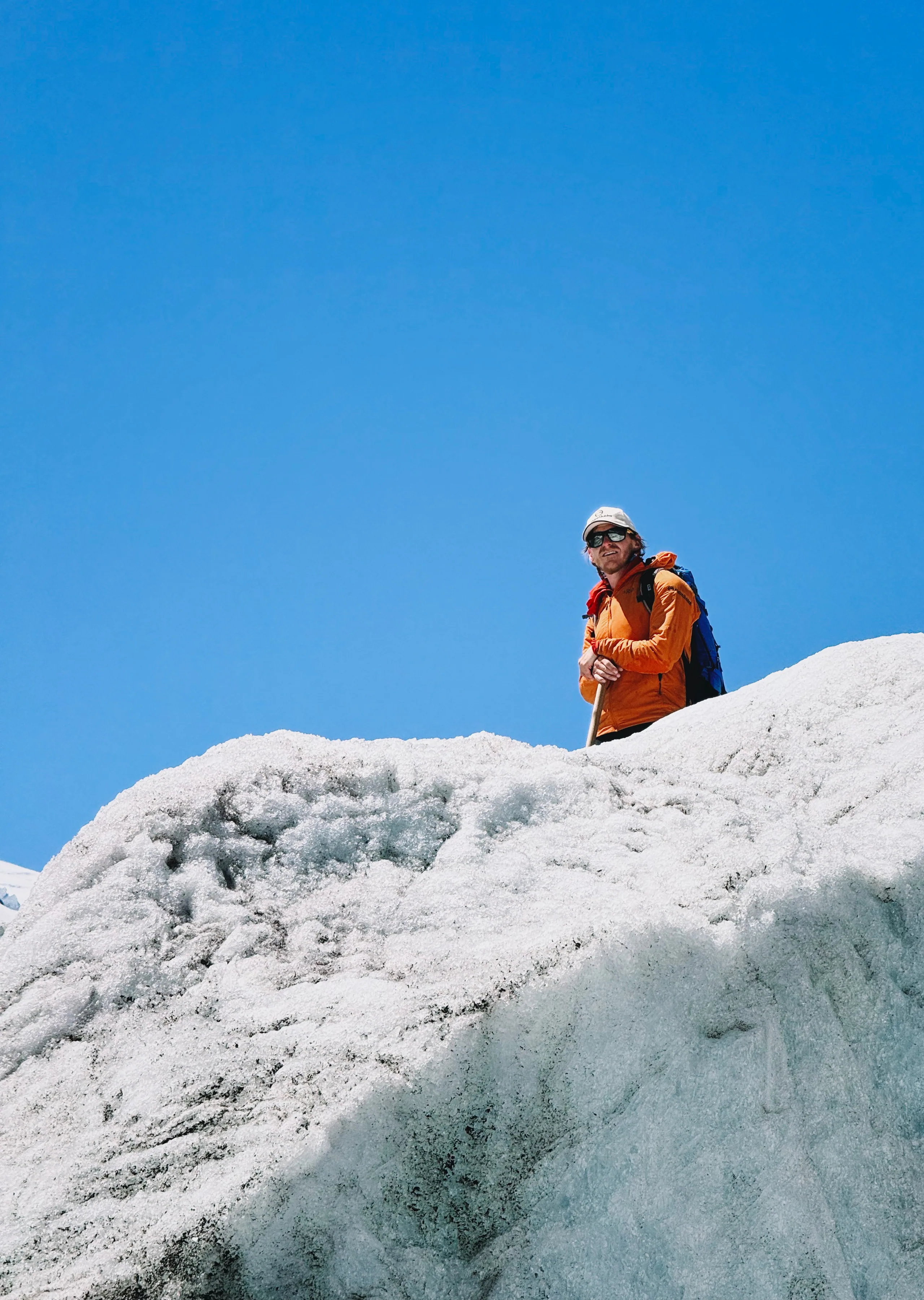 A glacier guide climbing through sculpted blue ice