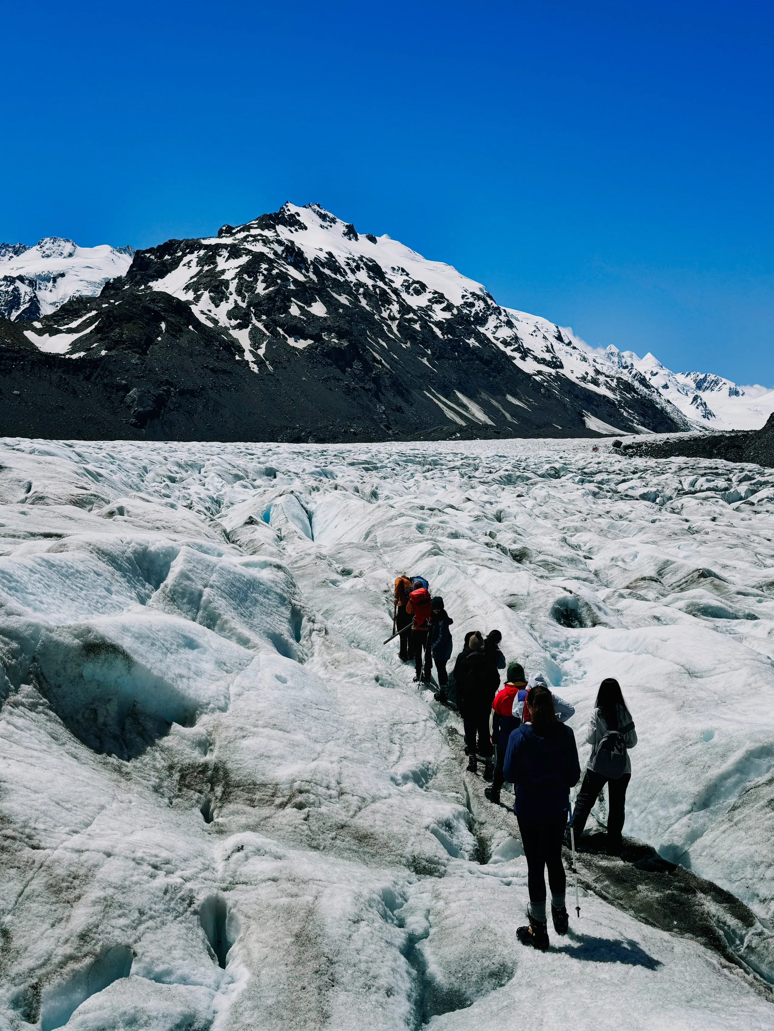 A hiker among ridges of white glacier ice