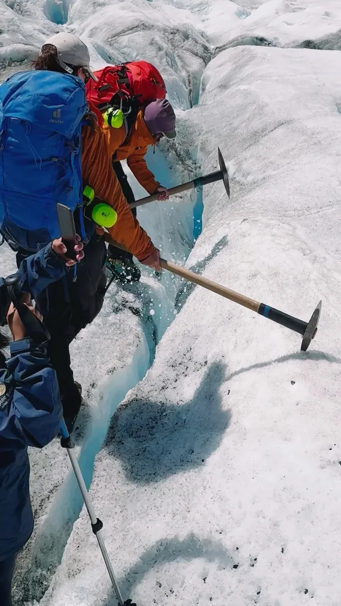 A hiker stepping through layered glacier ice