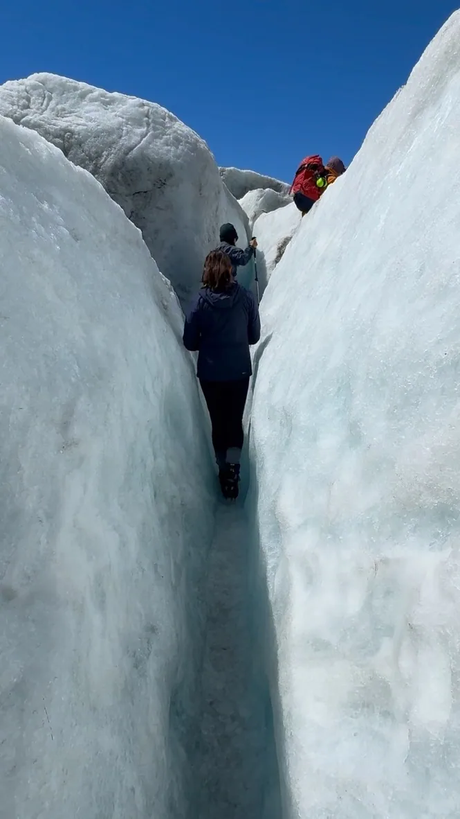 The hiking group moving between tall glacier formations