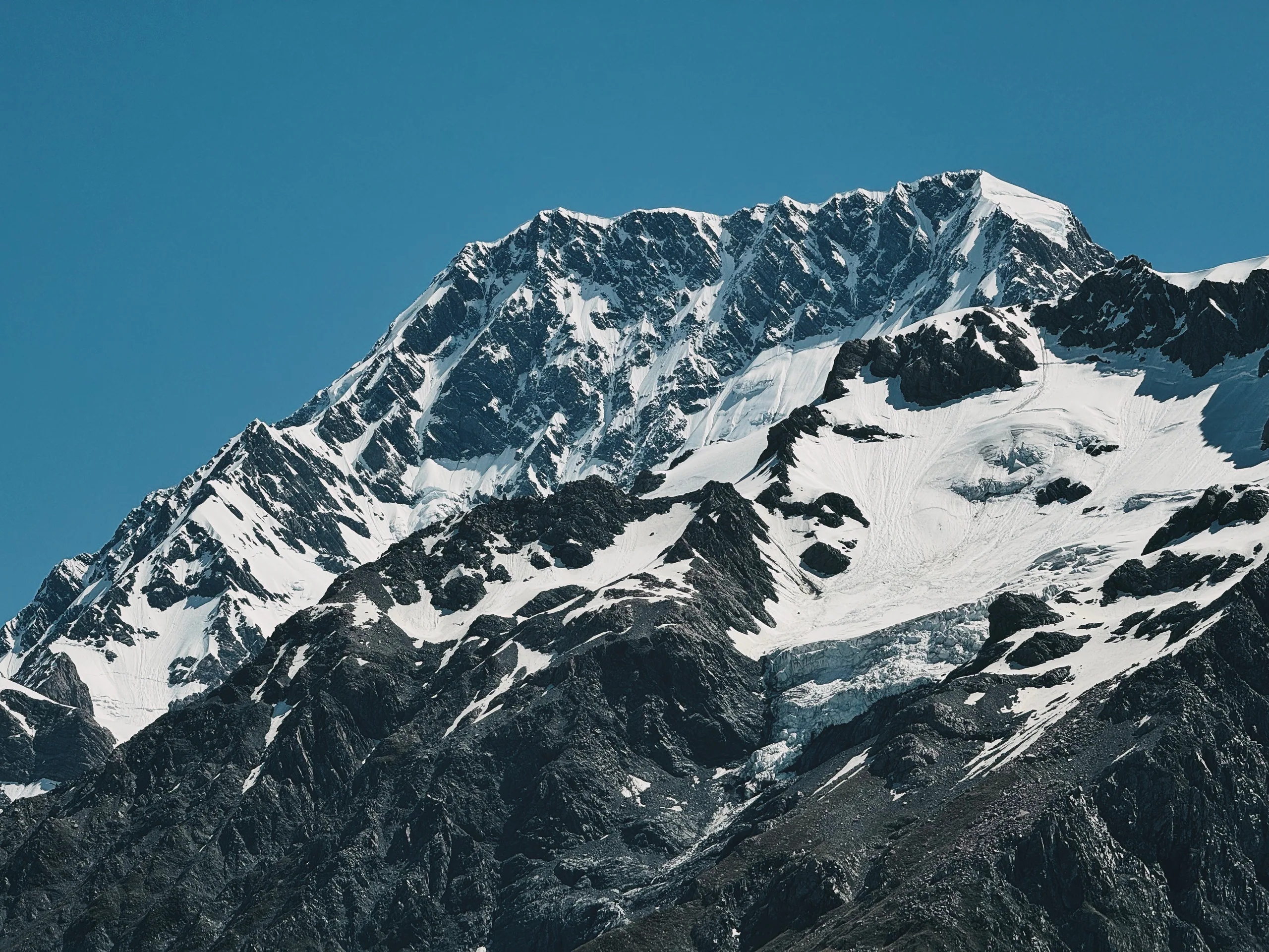 Dark moraine contrasting with bright glacier ice and snowy mountains