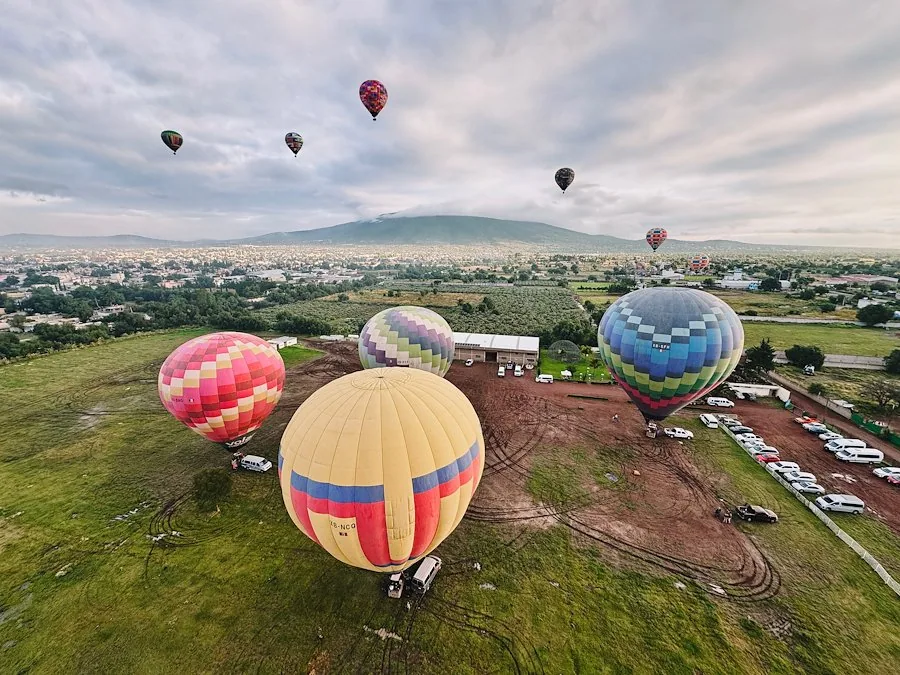 Hot air balloons lifting into the cloudy morning sky