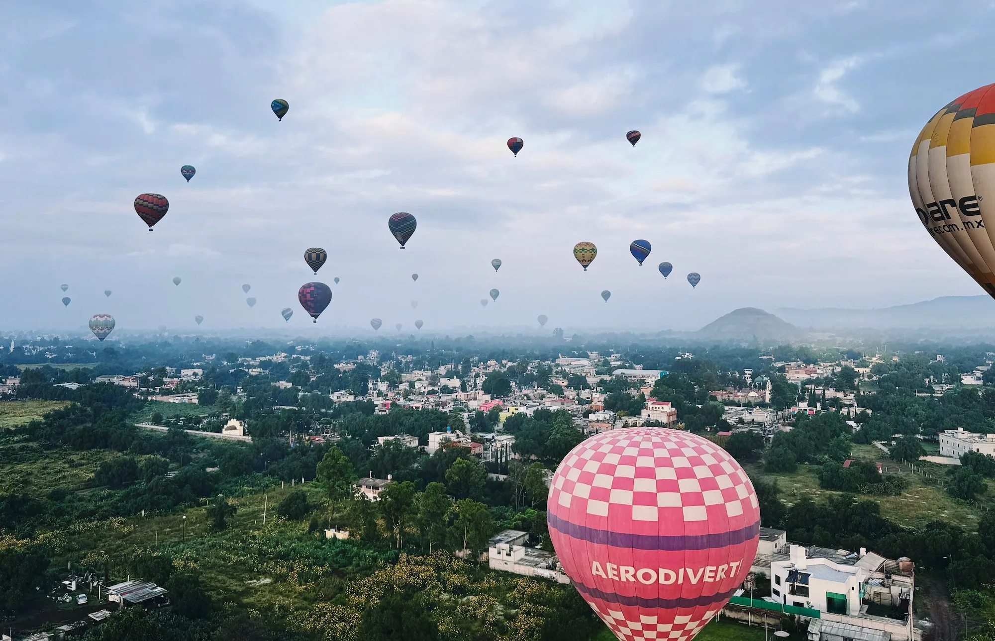 Dozens of hot air balloons spread across the Teotihuacan sky