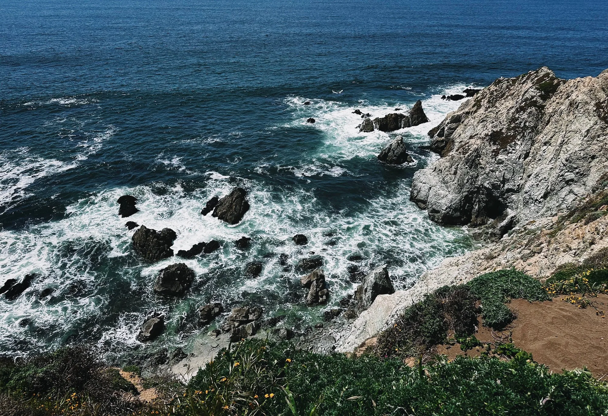 The ocean breaking far below the cliff-edge trail